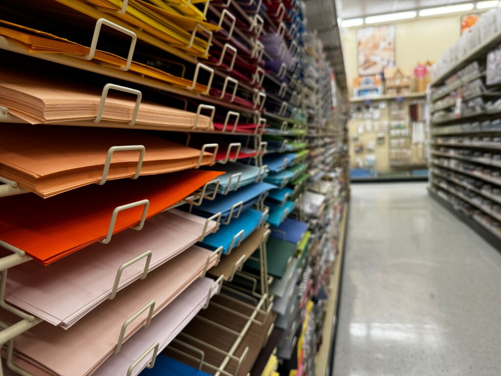 Multi Colored Paper Sheets Stacked On Shelves In A Craft Store Aisle
